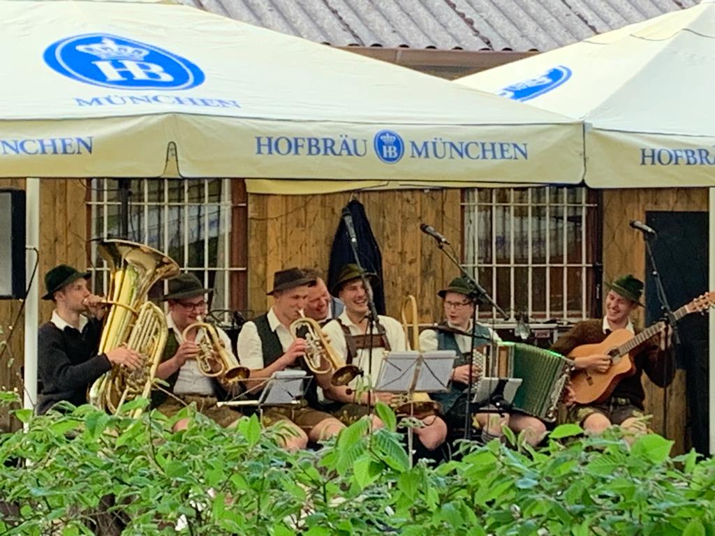 eine Band mit jungen 7 Männern sitzen draussen und spielt Musik auf verschiedenen Instrumenten