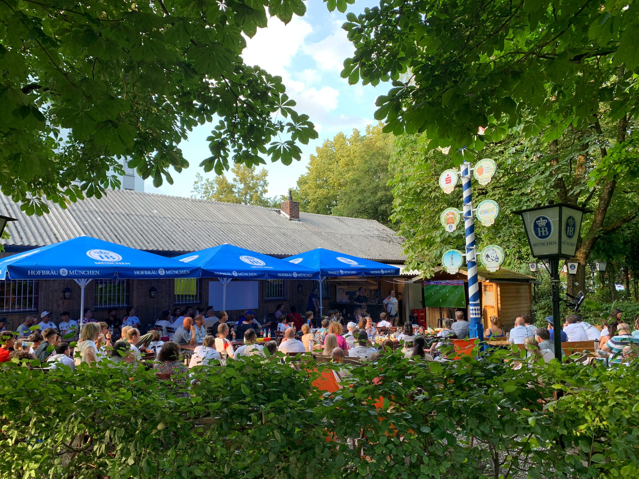 Aussenansicht der Vereinsheim-Terrasse mit vielen Personen die auf Stühlen sitzen