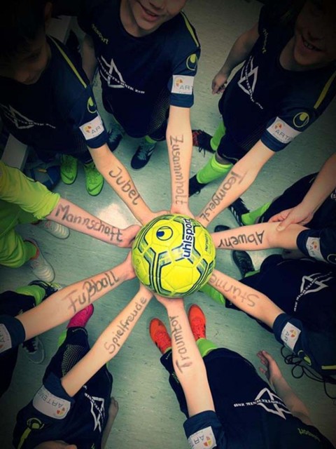 Team Werte 9 Arme mit Aufschriften der Werte halten zusammen einen gelben Ball