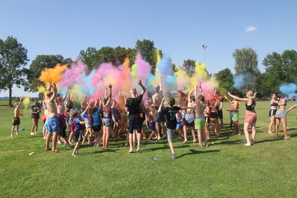 viele Kinder und Jugendliche werfen verschiedene Farbpulver in die Luft