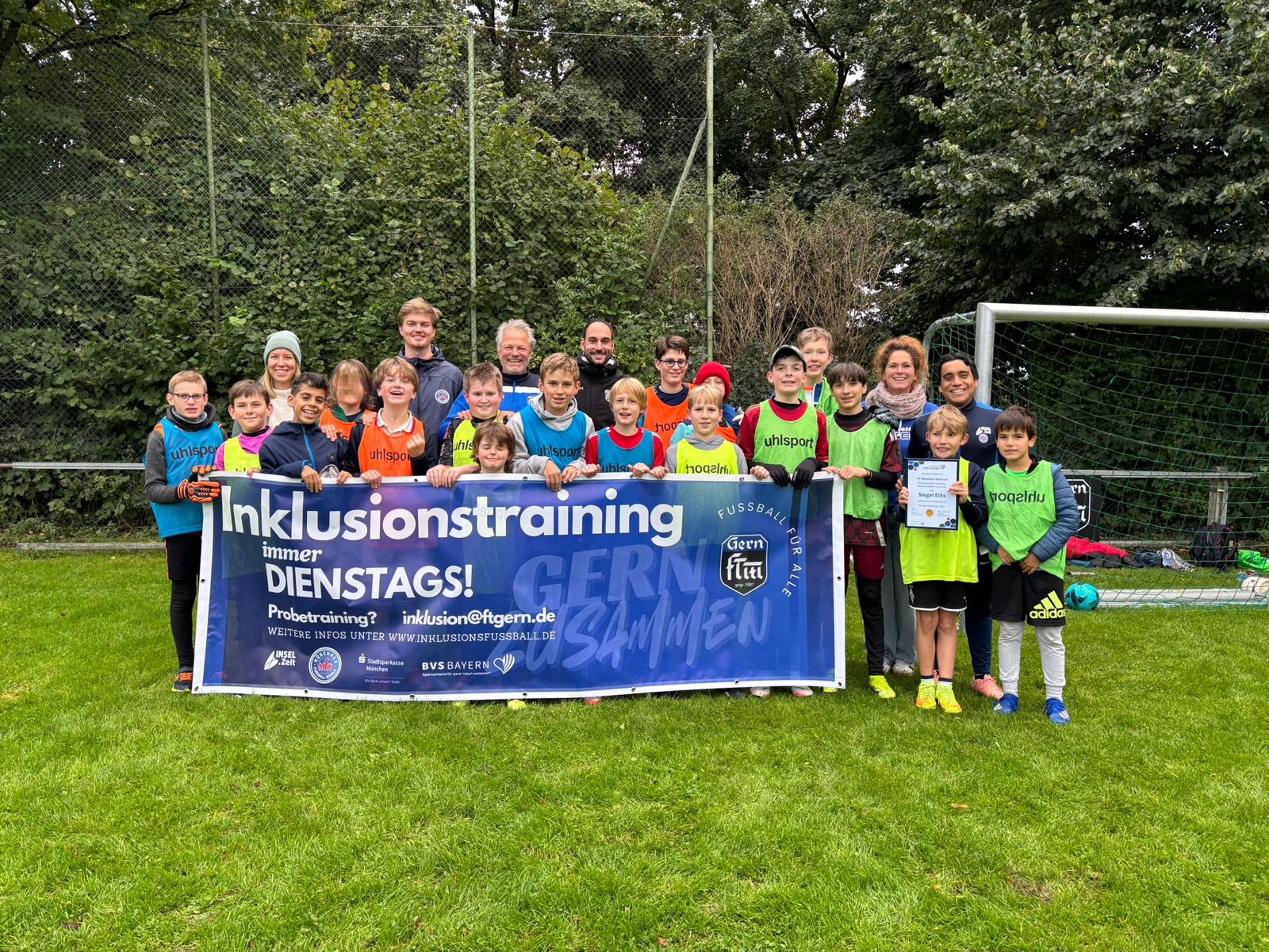 Inklusions-Abteilung FT Gern Viele Kinder und Erwachsene in bunten Trikots halten ein blaues großes Banner hoch